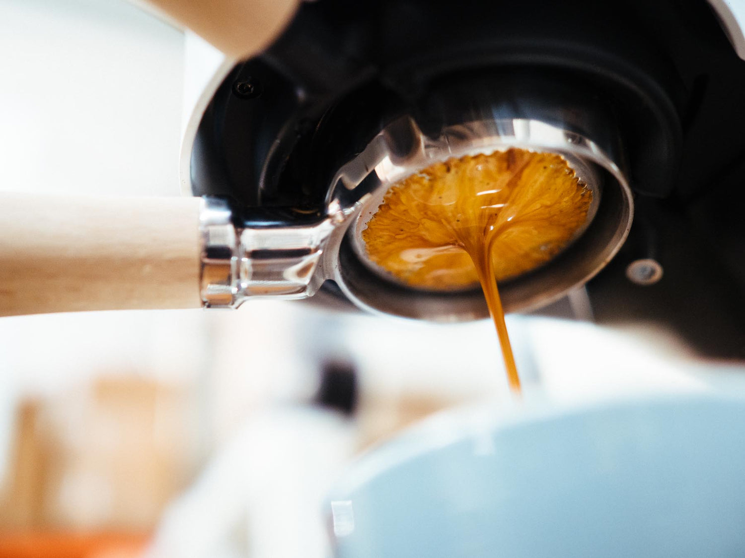 Coffee being poured from a portafilter into a coffee machine.