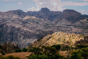 Walled village nestled in a mountainous landscape of Yemen with a clear sky.